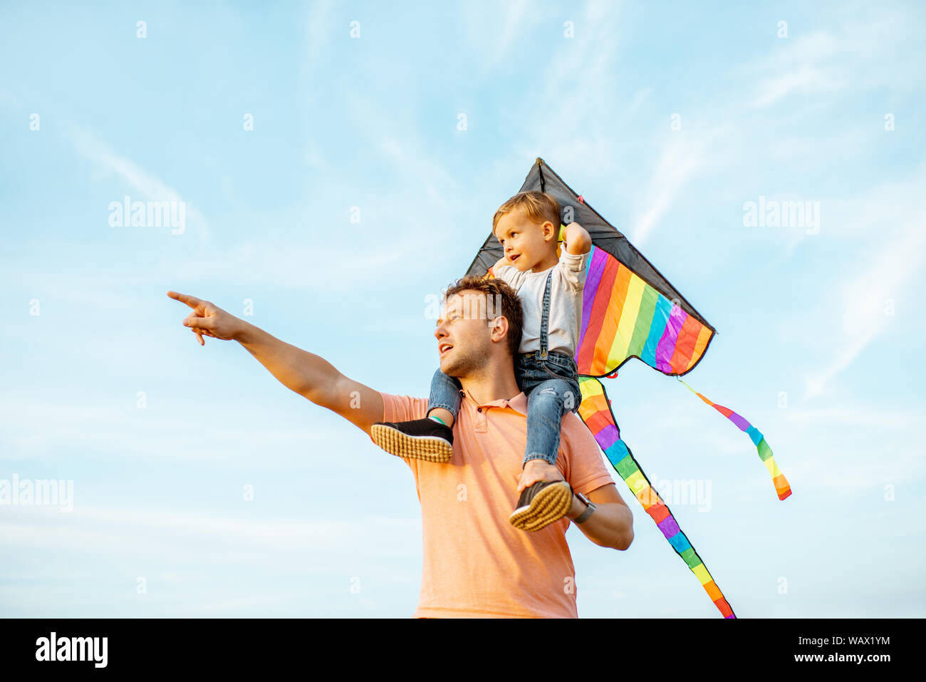 Portrait d'un heureux père et fils sur les épaules avec l'air sur le cerf-volant coloré fond de ciel bleu. Concept d'une famille heureuse et d'acti Banque D'Images