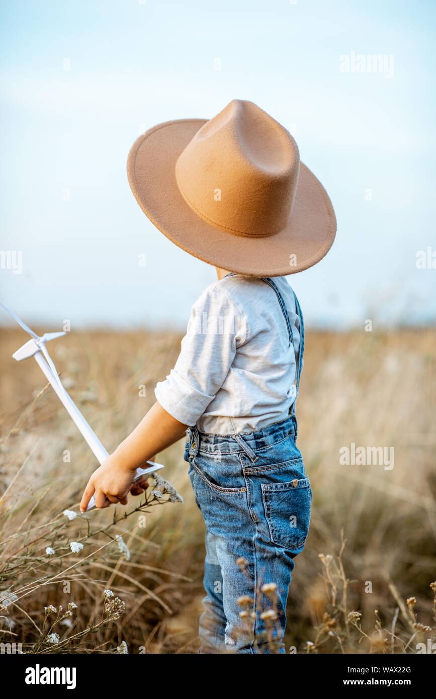 Jeune garçon curieux Playing with toy wind turbine sur le terrain, étudier comment fonctionne l'énergie verte d'un jeune âge Banque D'Images