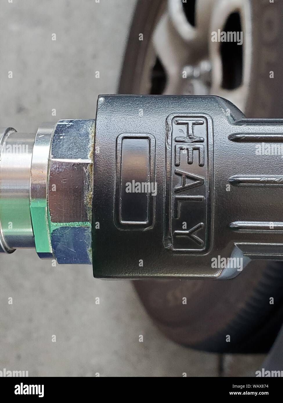 Close-up de logo pour Healy sur la récupération des vapeurs d'un flexible de pompe à gaz, avec pneu de voiture visible, à une station-service, le 21 août 2019. () Banque D'Images