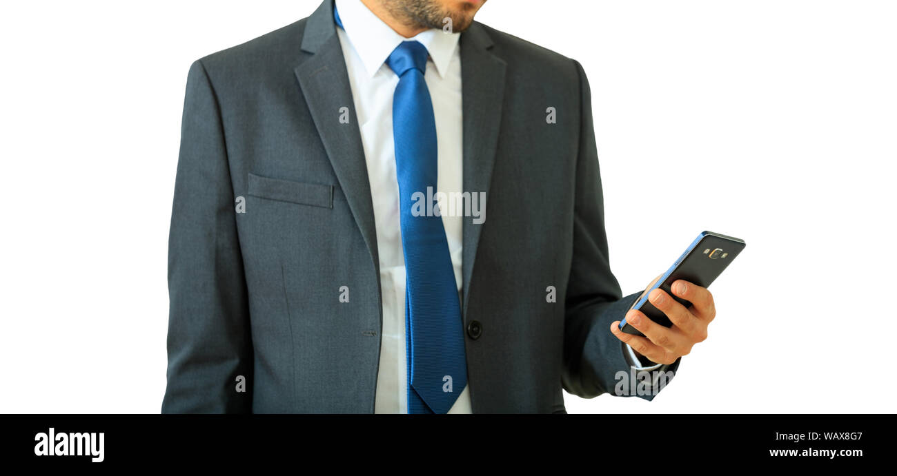 L'homme à l'aide de mobile smart phone, découpe isolées contre l'arrière-plan blanc, vue en gros plan. Jeune homme en costume gris et cravate bleue Banque D'Images