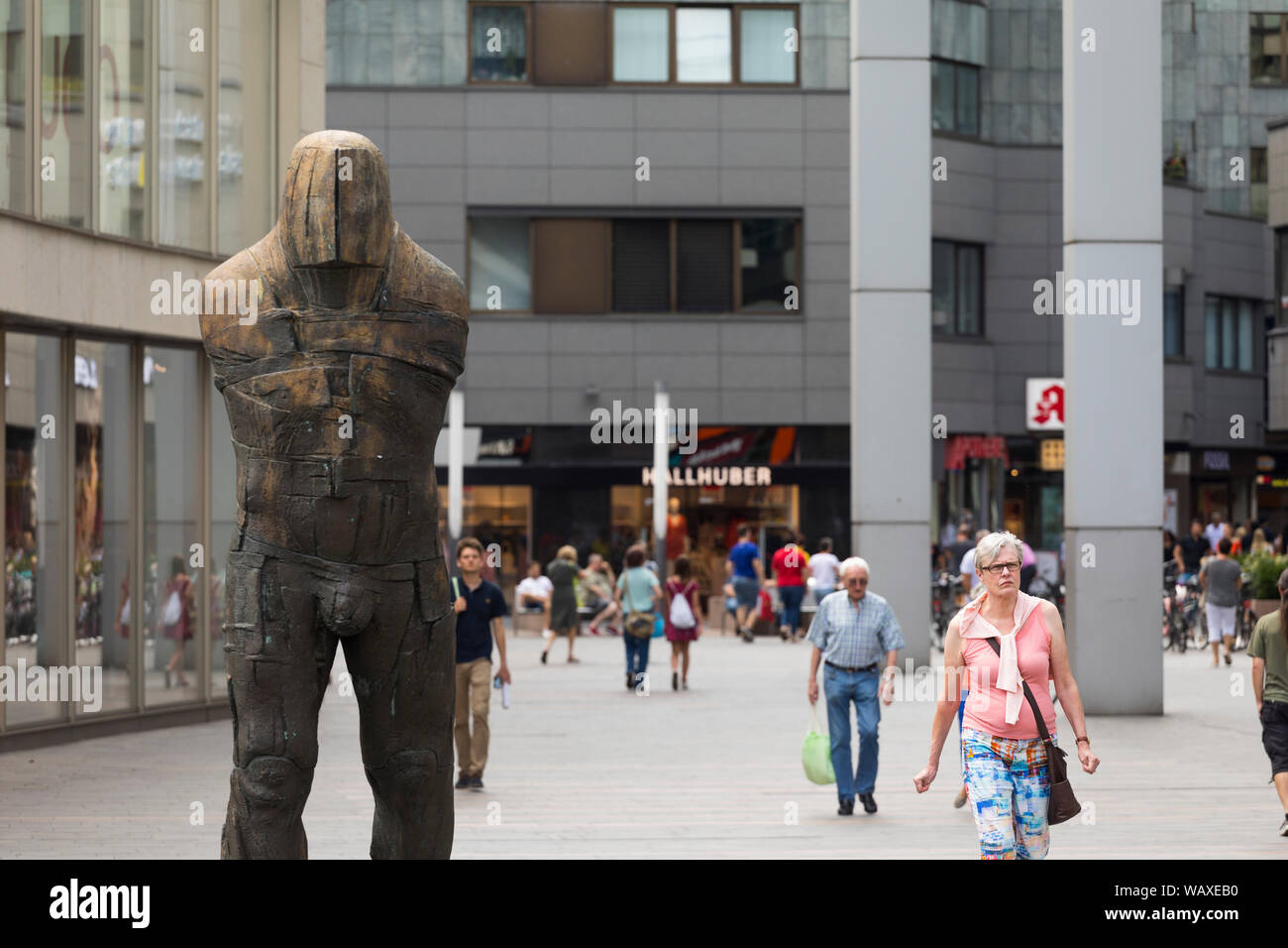 Femme passant résumé statue d'une figure masculine dans les quartiers shopping street, Mainz, Allemagne Banque D'Images