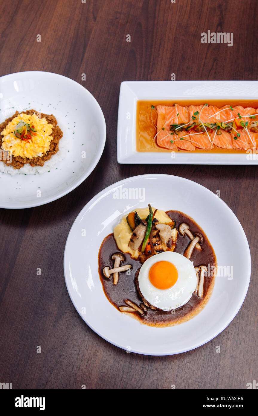 Porc épicé japonais Tan Tan sur du riz, salade de saumon tataki et hamburger steak avec des oeufs au plat et de champignon. Vue de dessus shot Banque D'Images