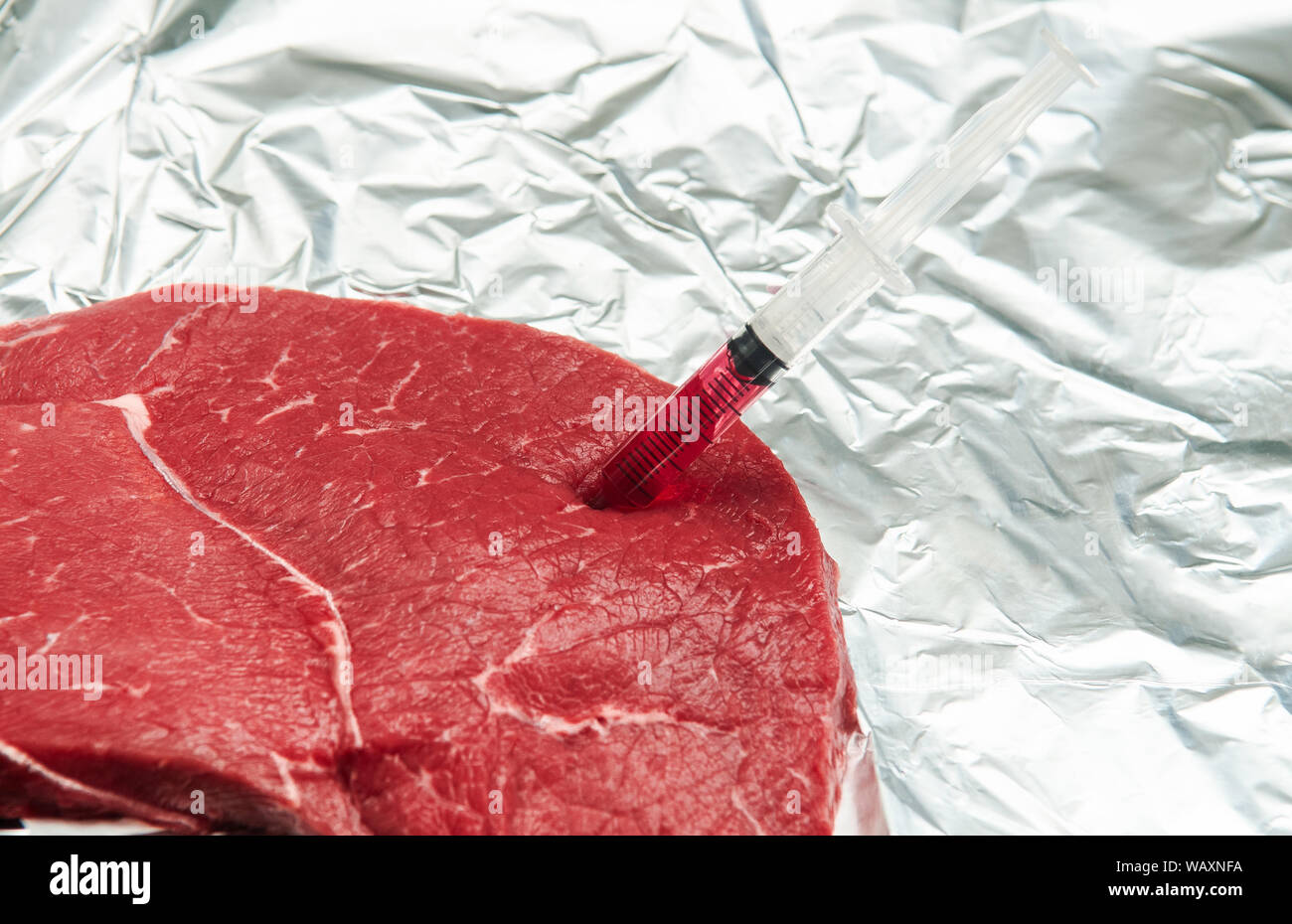 Hormone ou antibiotique de la viande contaminée - l'injection de produit chimique dans la viande rouge avec seringue isolé sur blanc - l'industrie des aliments malsains Banque D'Images
