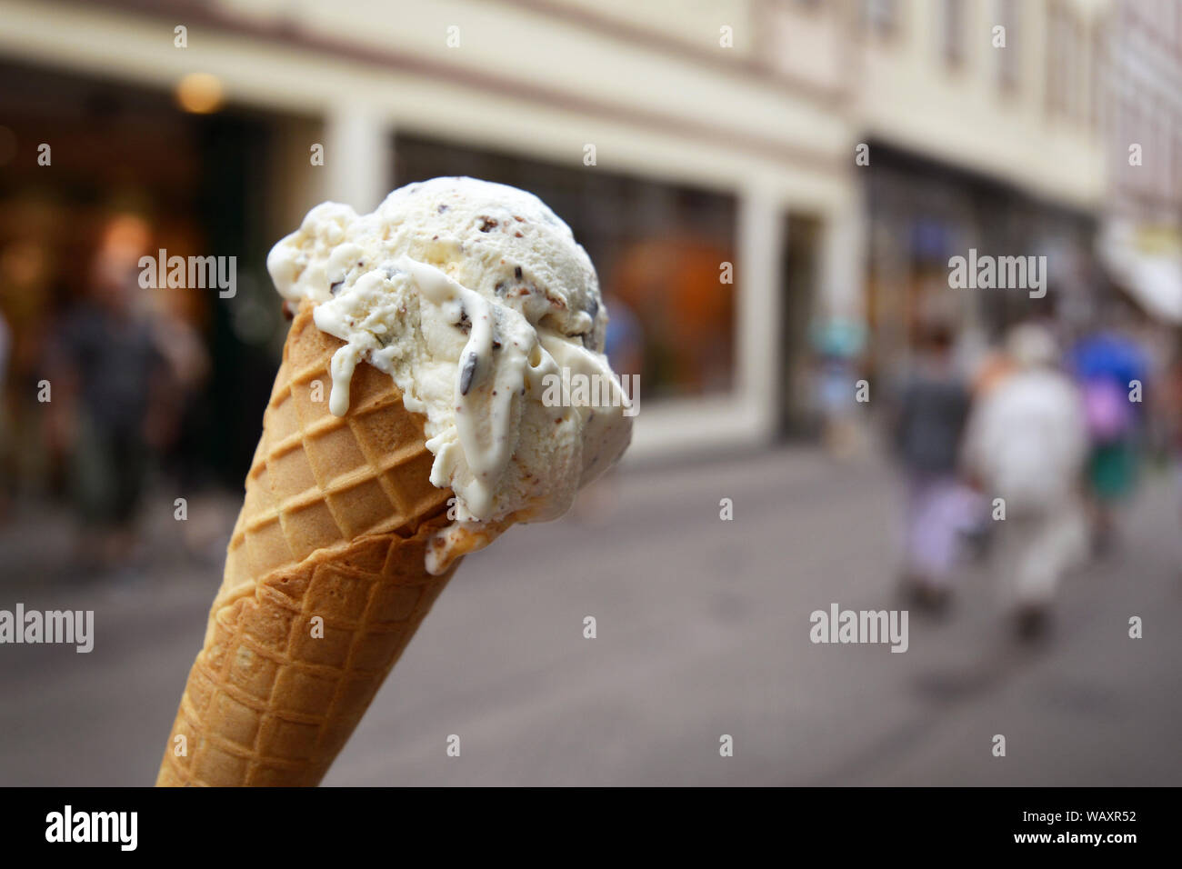 Close up du cône avec la vanille avec morceaux de chocolat avec de la crème glacée de la ville floues en arrière-plan de scène Banque D'Images