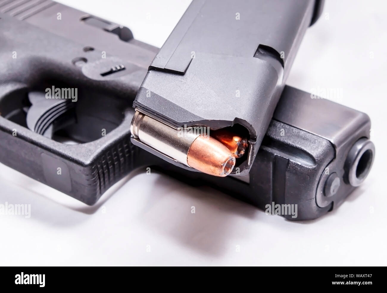 Un pistolet 9 mm chargé magazine au sommet d'un pistolet 9 mm noir sur fond blanc Banque D'Images