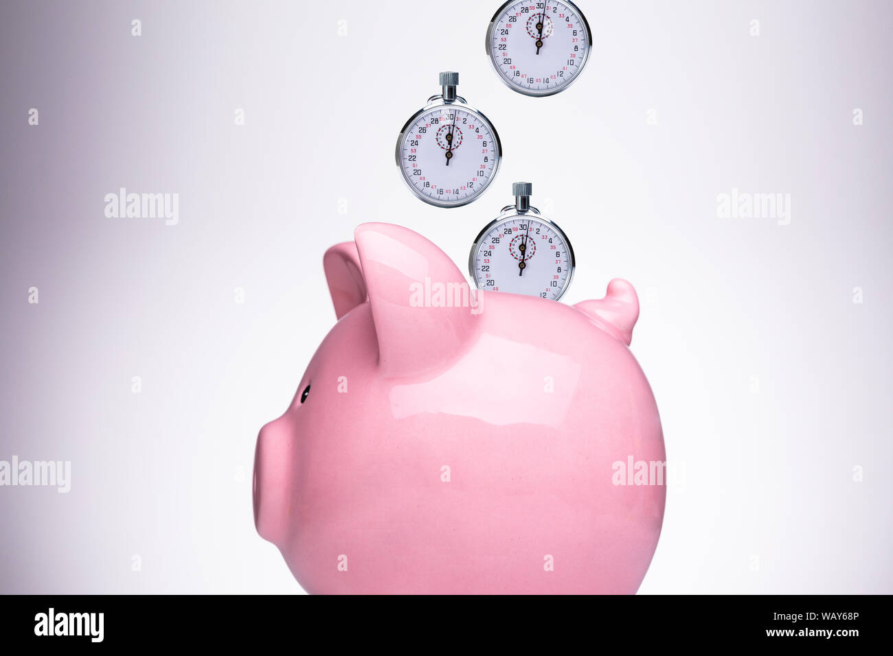 Close-up of Pink Piggy Bank avec chronomètre contre fond blanc Banque D'Images