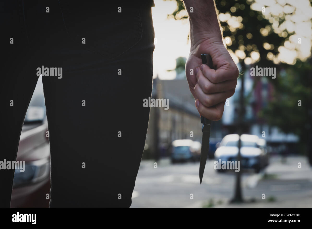 Un voleur ou un tueur personne avec un couteau dans la rue avant l'obscurité. Vol qualifié crime concept. Banque D'Images