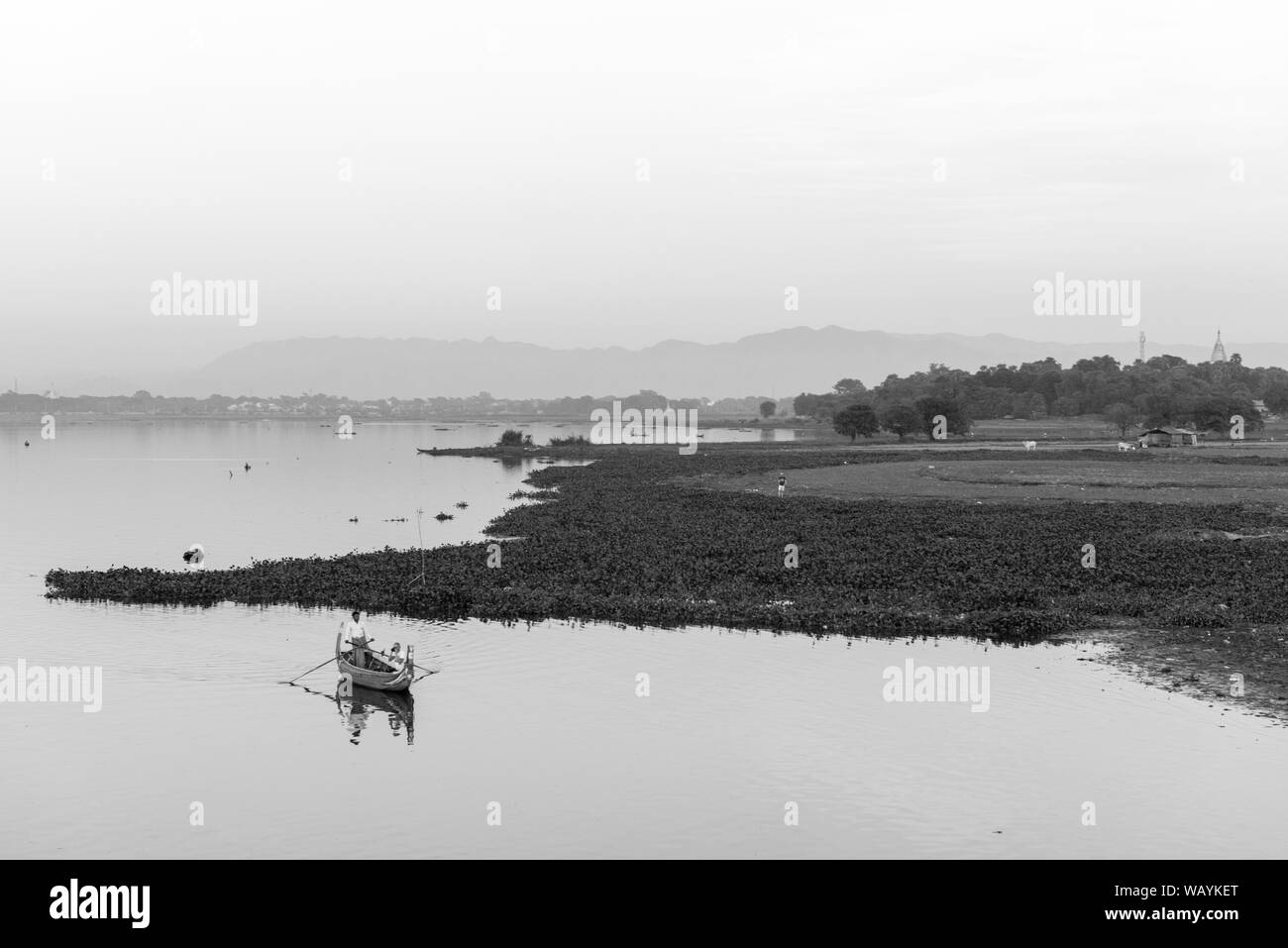 MANDALAY, MYANMAR - 03 décembre, 2018 : Noir et blanc photo de soleil colorés vue depuis le pont U Bein avec bateaux locaux à Mandalay, Myanmar Banque D'Images