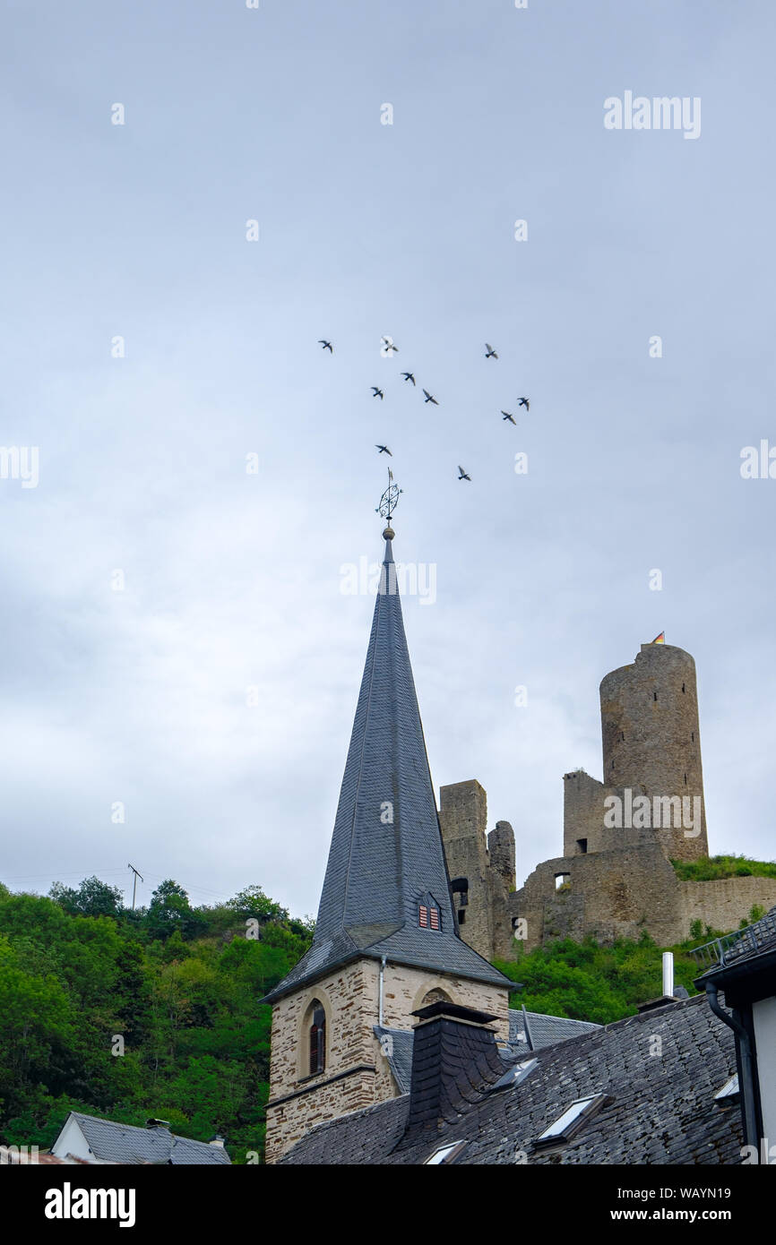 Église paroissiale église et château de Lowenburg avec le vol des oiseaux dans l'arrière-plan, dans le village pittoresque de Monreal dans la région de l'Eifel, Allemagne Banque D'Images