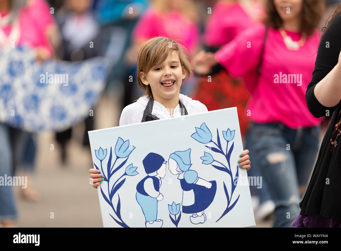 Holland, Michigan, États-Unis - 11 mai 2019 : Le Temps des tulipes Parade, femme l'accompagnement des enfants afficher leurs œuvres connexes néerlandais pendant la parade Banque D'Images