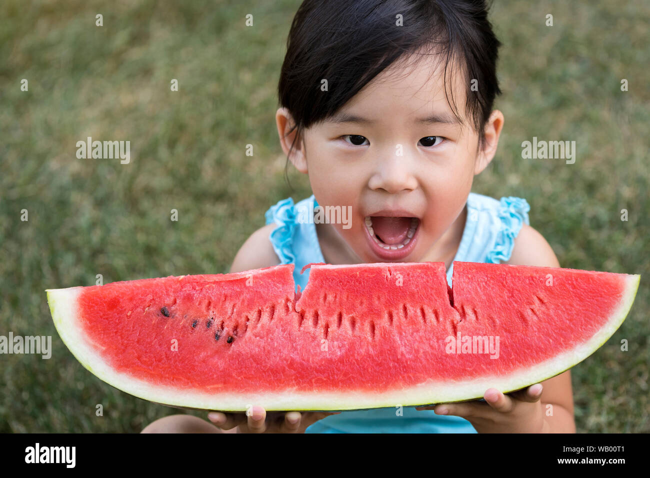 Happy little girl des pastèques dans un jardin Banque D'Images