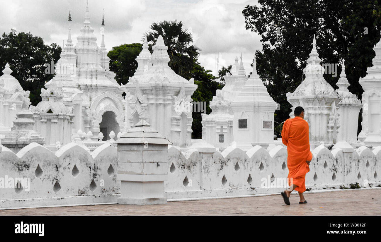 Le moine bouddhiste marcher en passant par un cimetière avec des tombes blanc et couleur orange pop up en Thaïlande Banque D'Images