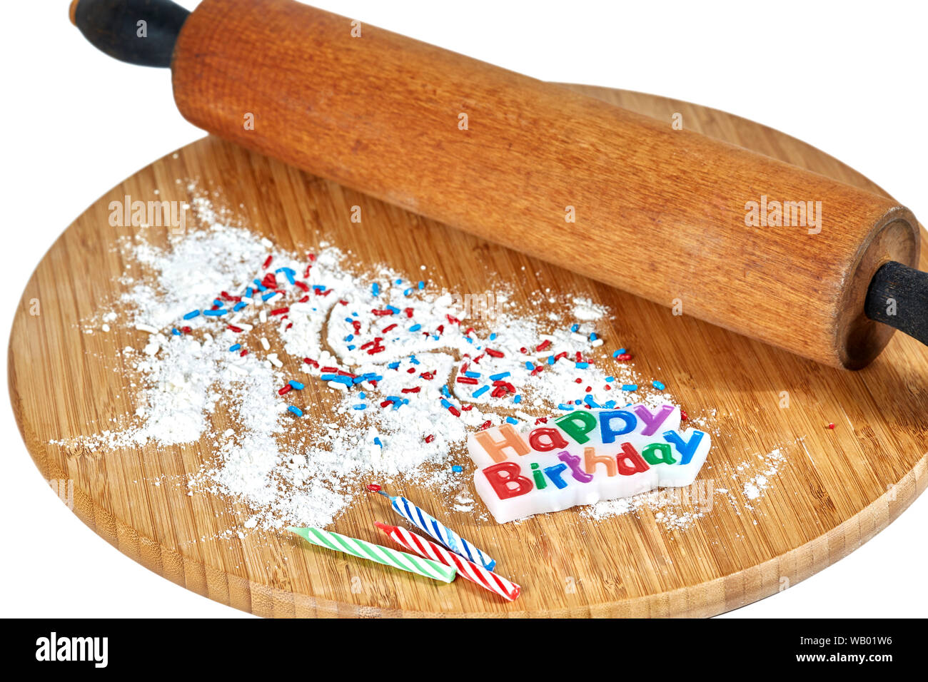 Un rouleau à pâtisserie en bois sur une planche à découper en bambou avec de la farine blanche et rouge, blanc et bleu et saupoudre de bougies d'anniversaire sur le conseil d'isolated on white Banque D'Images