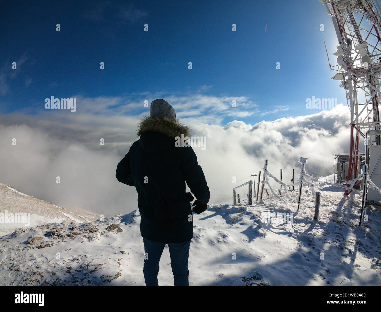 Homme debout sur le sommet de la montagne au bord auxquels les nuages et les vallées Banque D'Images