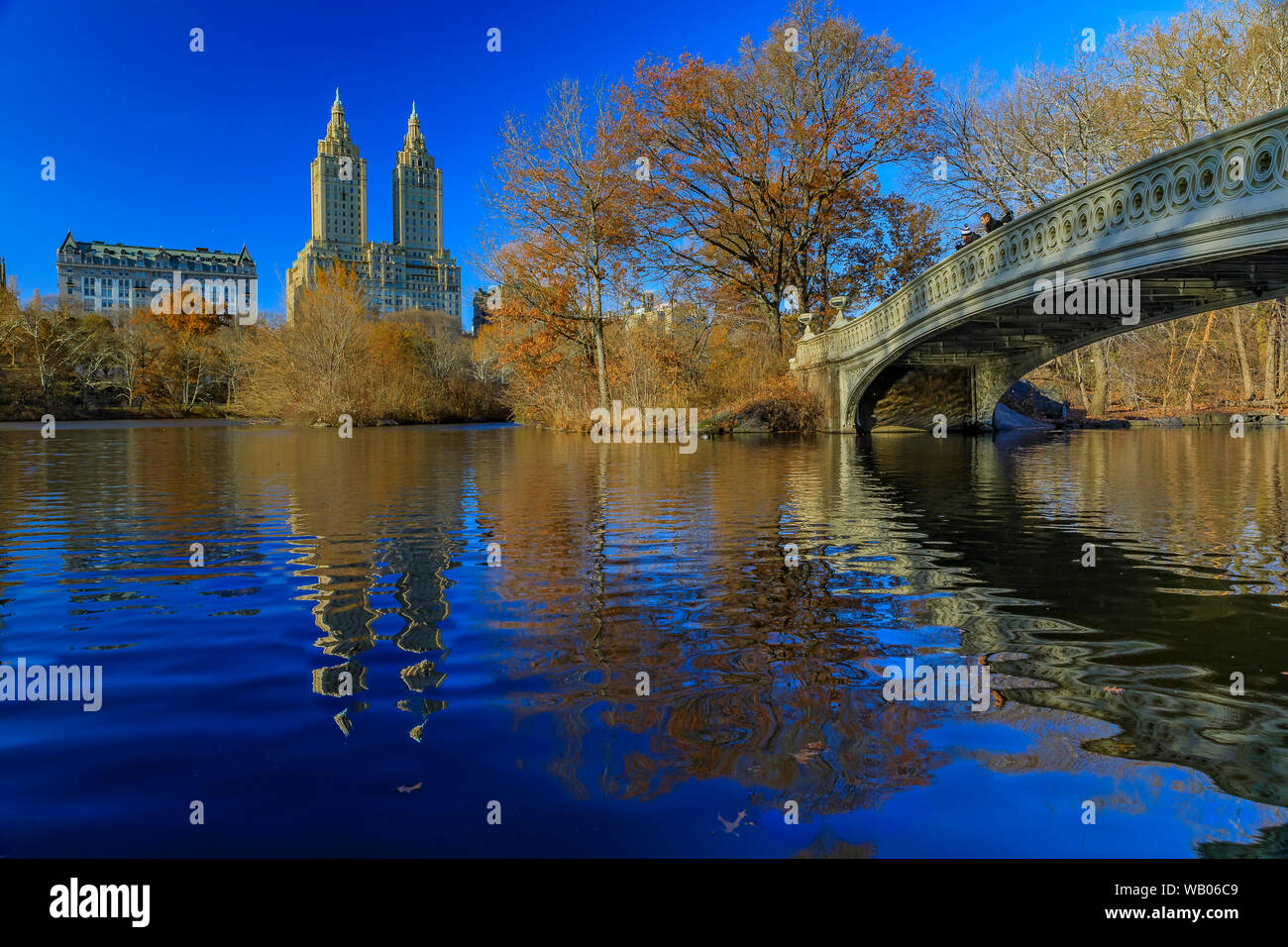 Pont Bow romantique sur le lac de Central Park, à New York à l'automne avec les immeubles de Manhattan en arrière-plan et de feuilles mortes dans l'avant-plan Banque D'Images