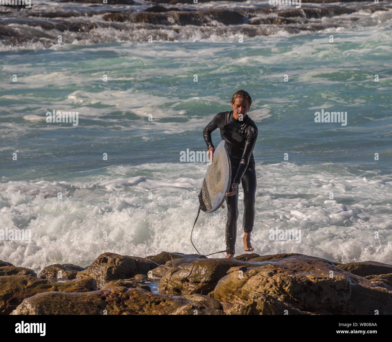 Mossel Bay, Afrique du Sud - un jeune homme sort du surfeur à l'eau à la Punt un populaire surf spot image au format paysage Banque D'Images