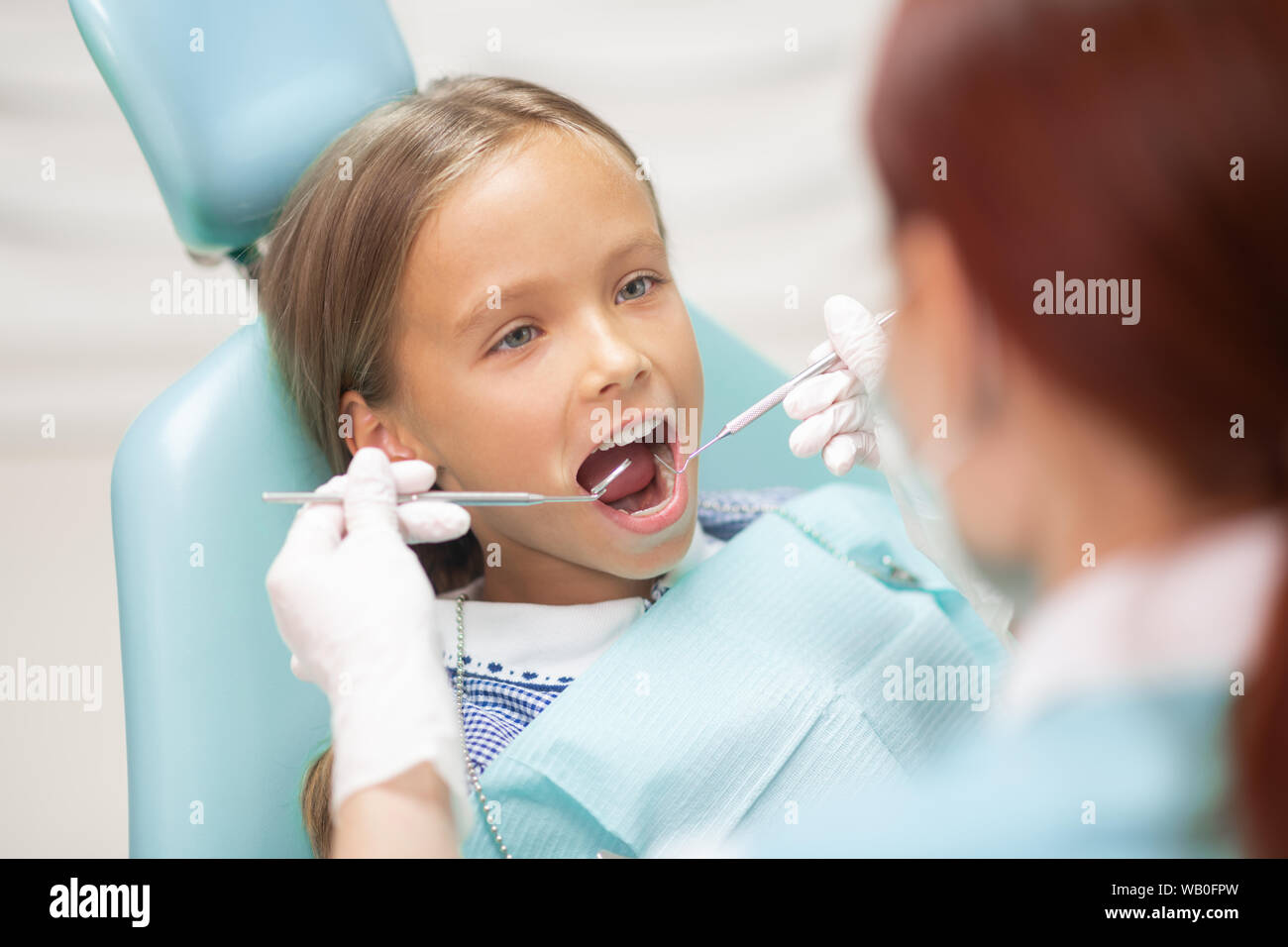 Blue-eyed girl d'ouvrir grand la bouche tout en visitant dentiste Banque D'Images