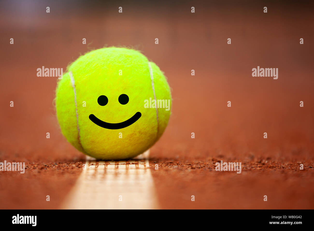 Emoji souriant sur balle de tennis se trouve sur la terre battue de près  Photo Stock - Alamy