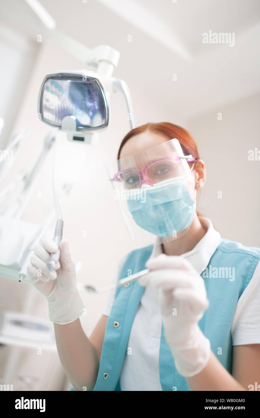 Rousse femelle professionnel dentiste dans un masque travaillant dur Banque D'Images
