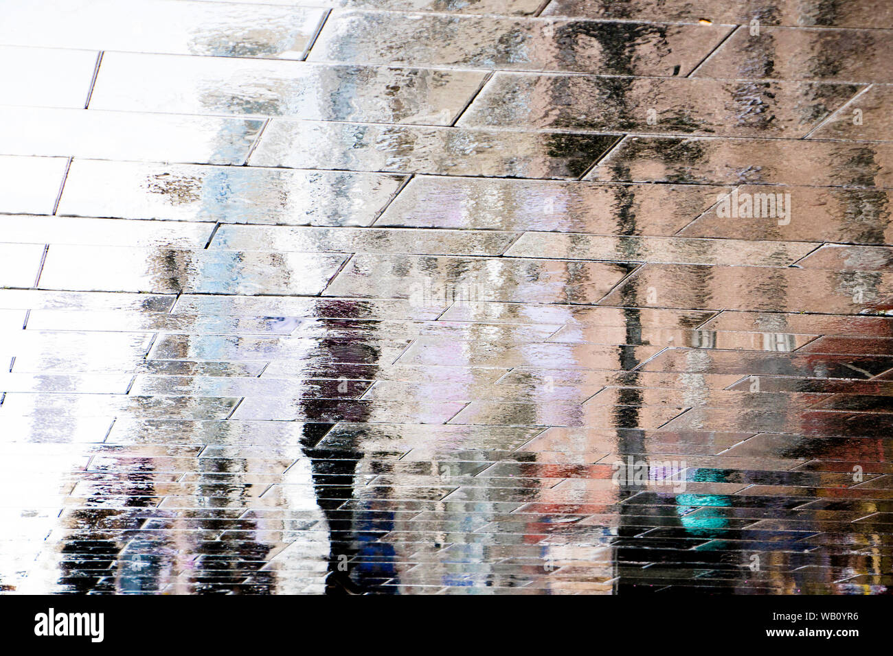 Réflexion floue ombre silhouettes de personnes marchant sur un caniche mouillé street dans la ville de la zone piétonne Banque D'Images