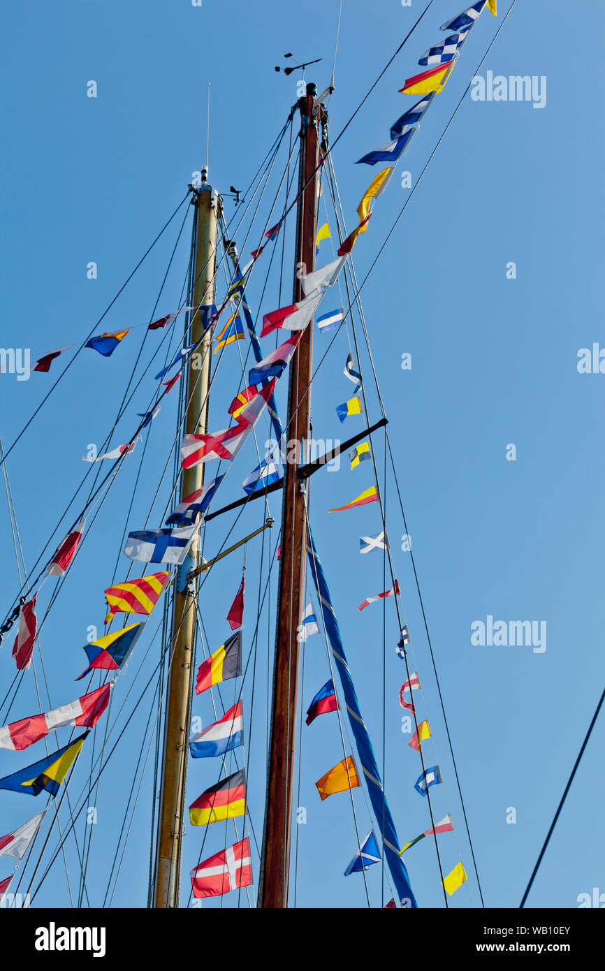 Différents drapeaux nautiques internationaux sur le mât d'un bateau à voile mât qui volent gaiement dans le vent Banque D'Images