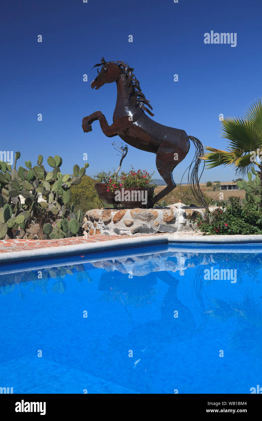 Une sculpture d'un cheval dansant à côté d'une piscine d''un complexe de luxe/villa Banque D'Images