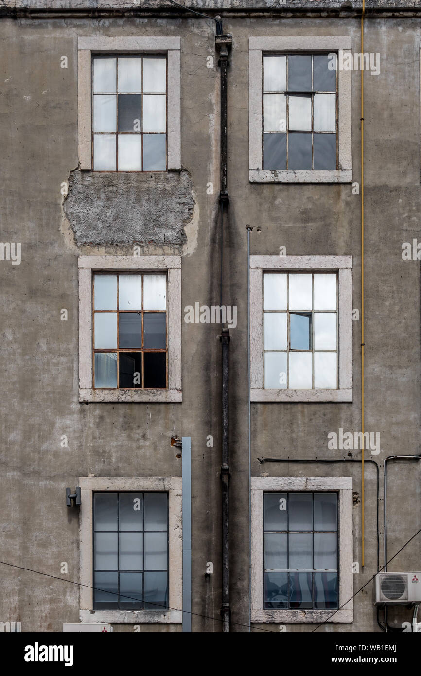 Closeup portrait détail vue de l'architecture de 3 rangées de fenêtres et  volets de l'état usé dans mur en béton façade de bâtiment industriel à Li  Photo Stock - Alamy