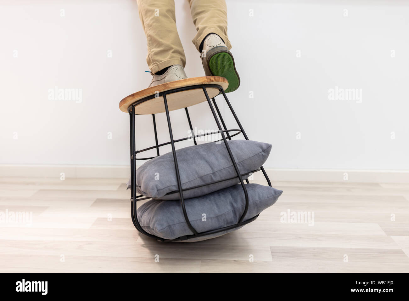 Homme debout sur le canapé et table sur le point de tomber sur le plancher Banque D'Images