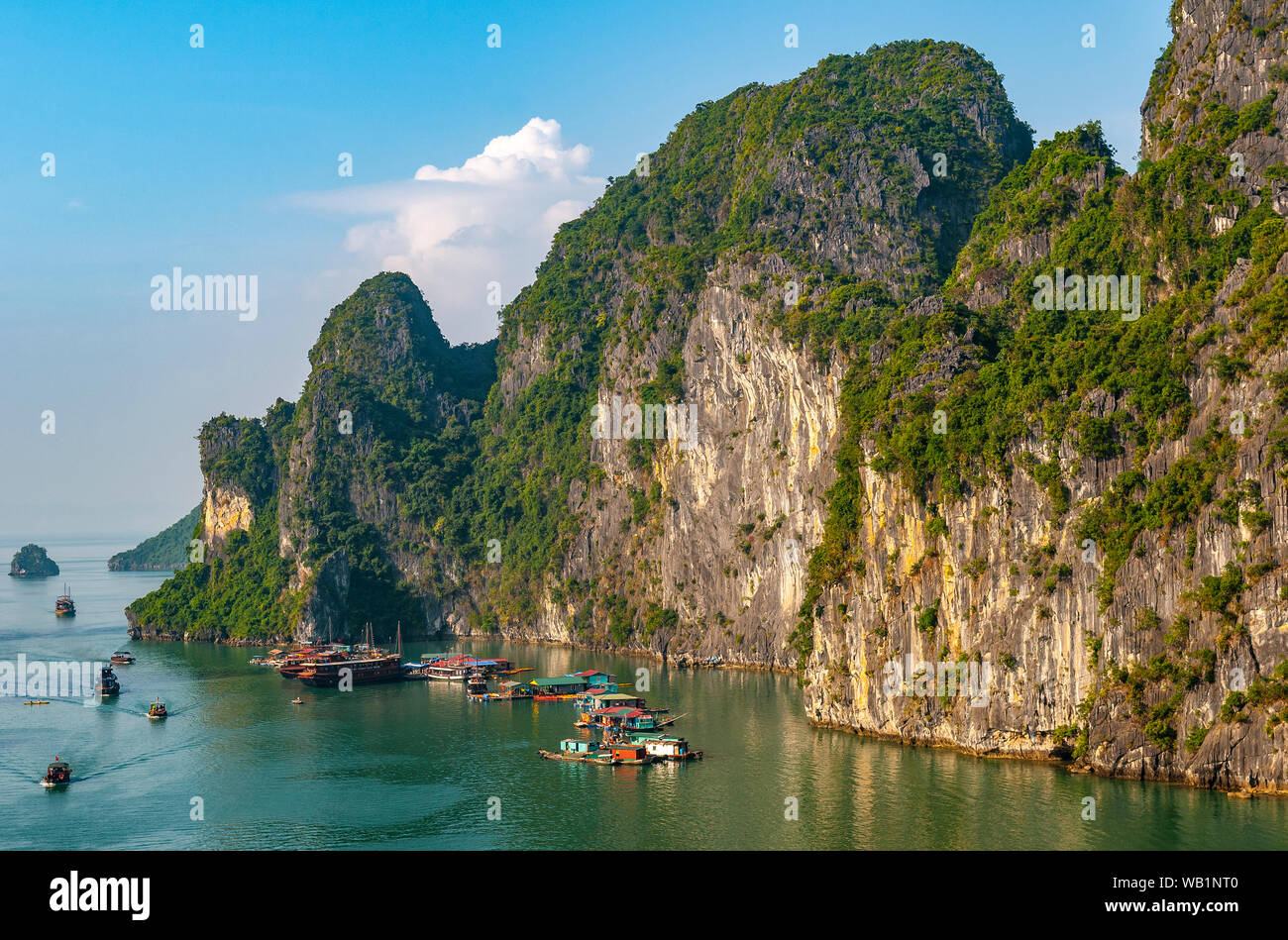 Un village flottant parmi les formations de roche karstique géologique de la Baie d'Halong au coucher du soleil, le nord du Vietnam. Banque D'Images