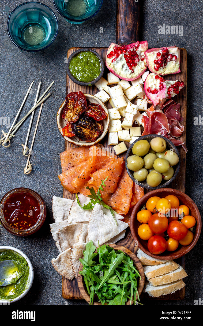 L'antipasto. Set de vin apéritif. Jambon Serrano, saumon fumé, tomates séchées et fromage frais d'olive, du vin à bord. Vue de dessus, l'arrière-plan gris cncrete Banque D'Images