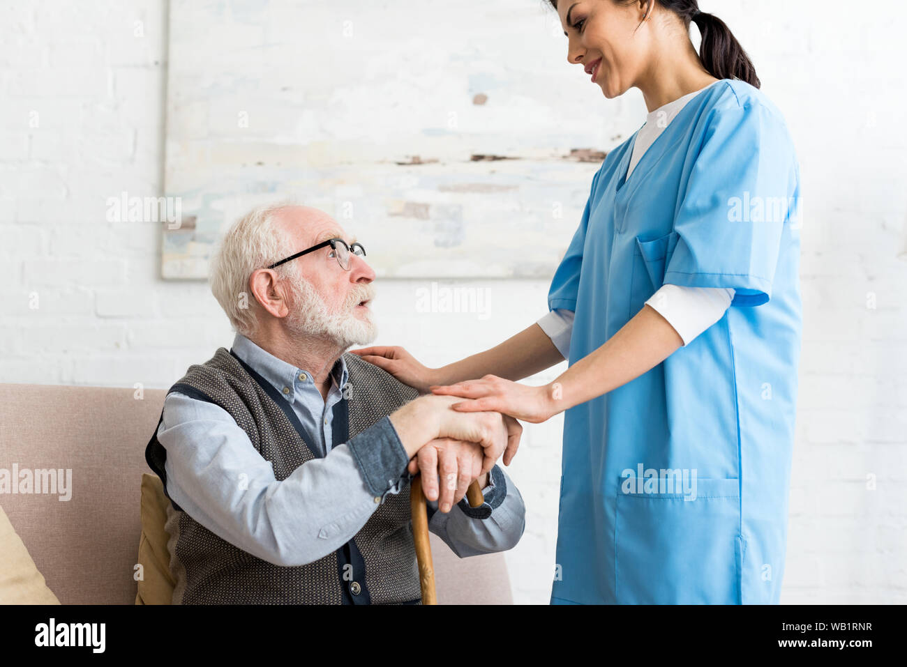 Vue latérale d'un homme âgé et nurse standing en chambre, à l'un l'autre Banque D'Images