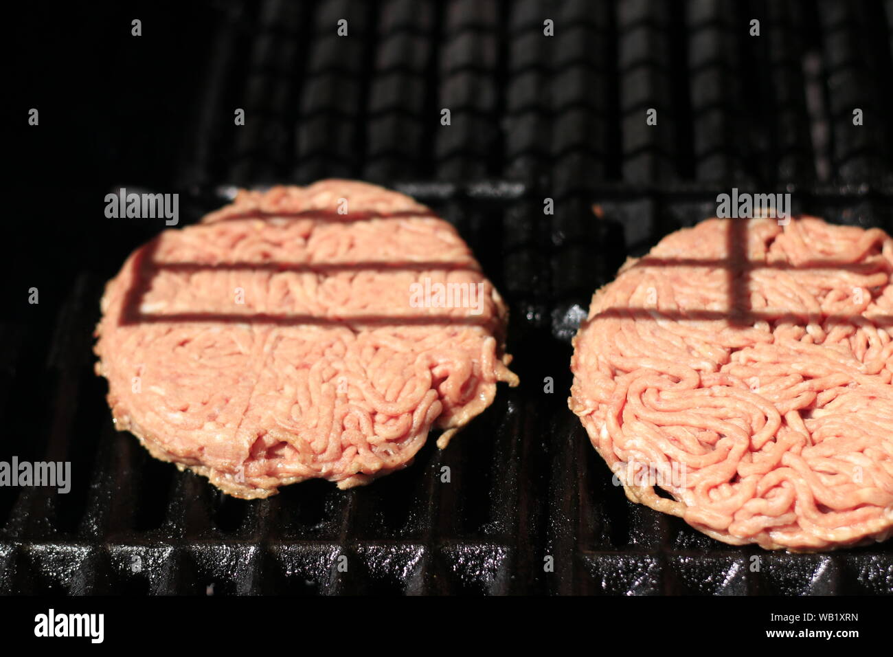 Les burgers sur bbq Barbecue grill au feu. La viande de l'alimentation - matières premières galettes sur le bbq Barbecue grill au feu. Shallow dof Banque D'Images