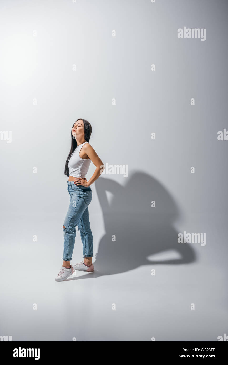 Sur toute la longueur de la belle jeune fille debout dans poser les mains sur les hanches et les yeux fermés Banque D'Images
