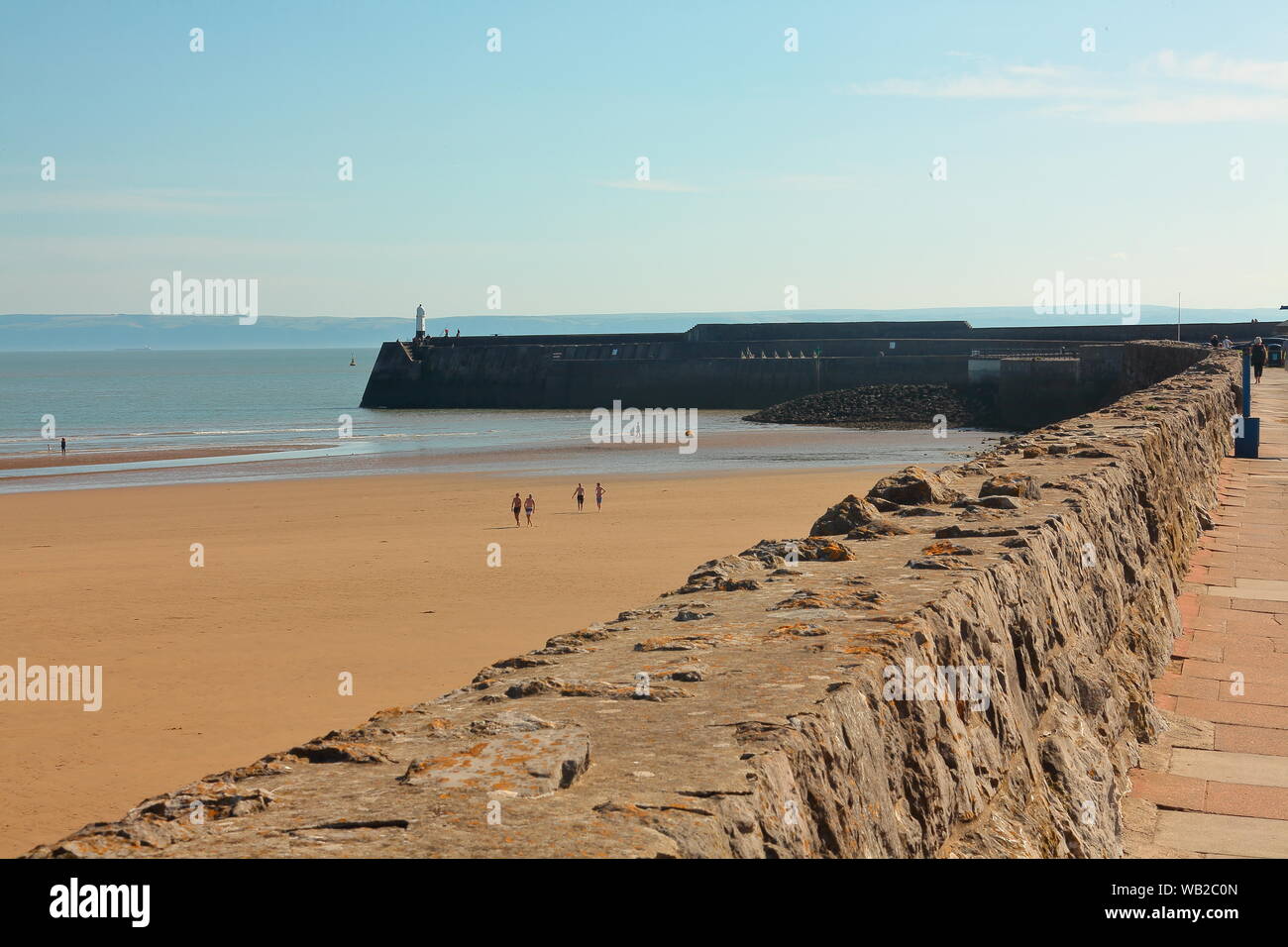 À la promenade le long du mur vers le phare à la fin de la jetée de navires d'avertissement des dangers de cette belle plage. Banque D'Images