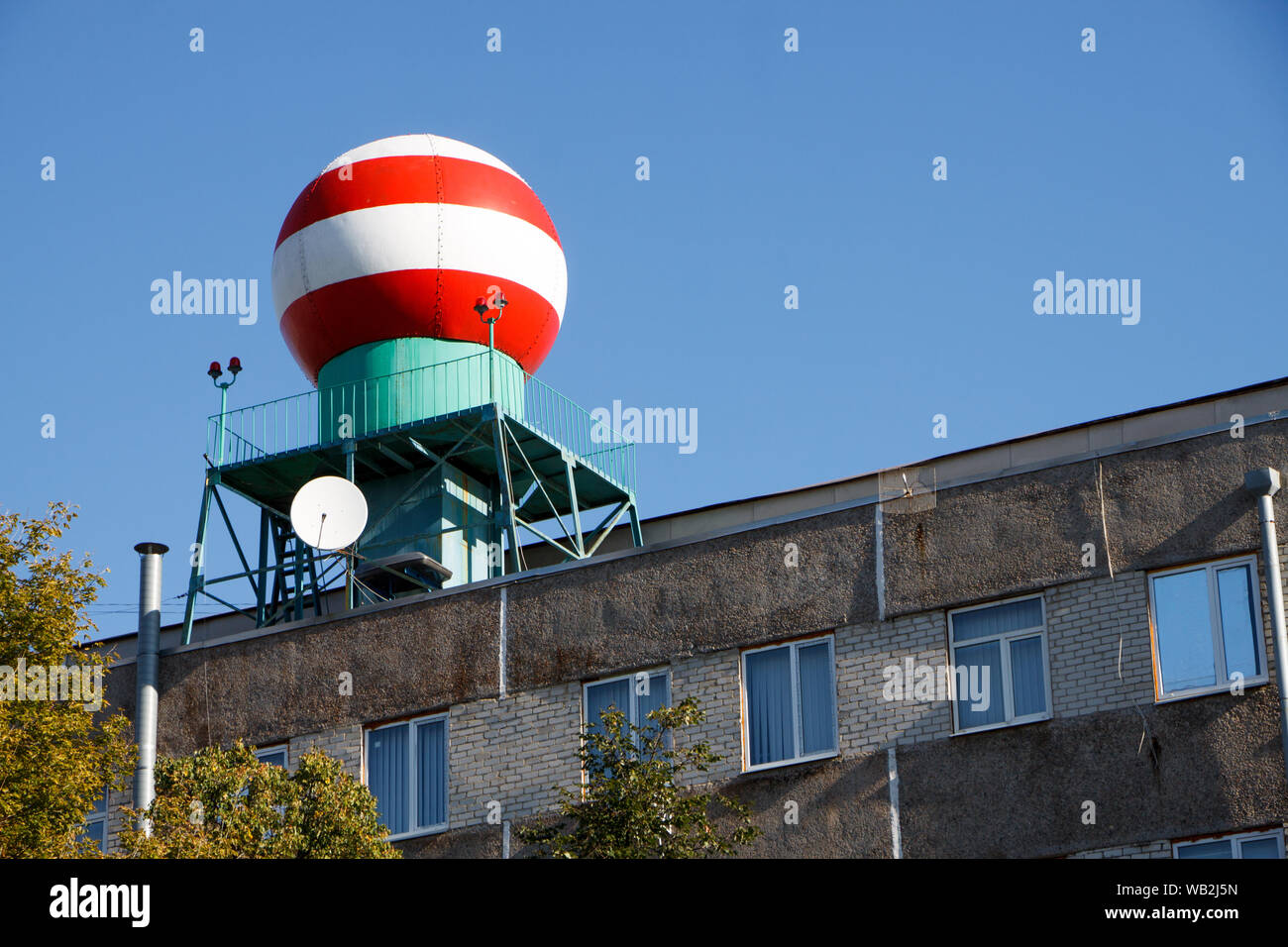 Vue de dessous de la sphère blanche rouge sur le bâtiment du service météorologique contre le ciel bleu Banque D'Images