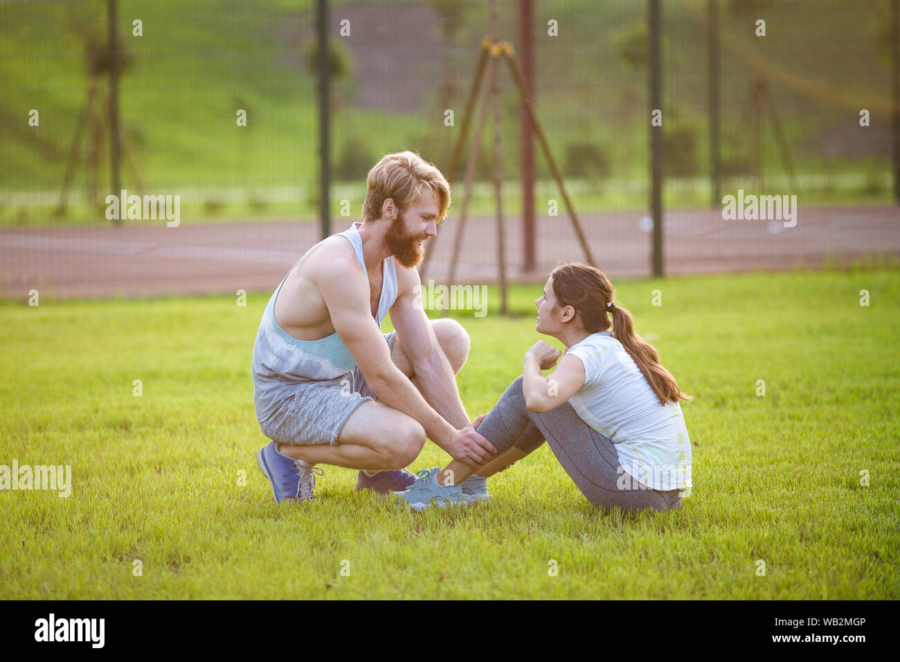 Remise en forme l'exercice abdominaux couple s'asseoir à l'extérieur dans l'herbe. Mettre en place les personnes qui travaillent à la formation. Woman doing abdominal crunches appuyez sur l'exercice avec Banque D'Images