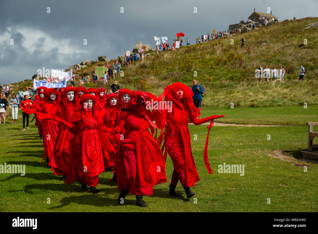 Porthmeor, St Ives, Cornwall, UK. La troupe de réserve de performance de la Brigade rebelle rouge à pied parmi les vacanciers tasing de conscience de la crise climatique. Banque D'Images