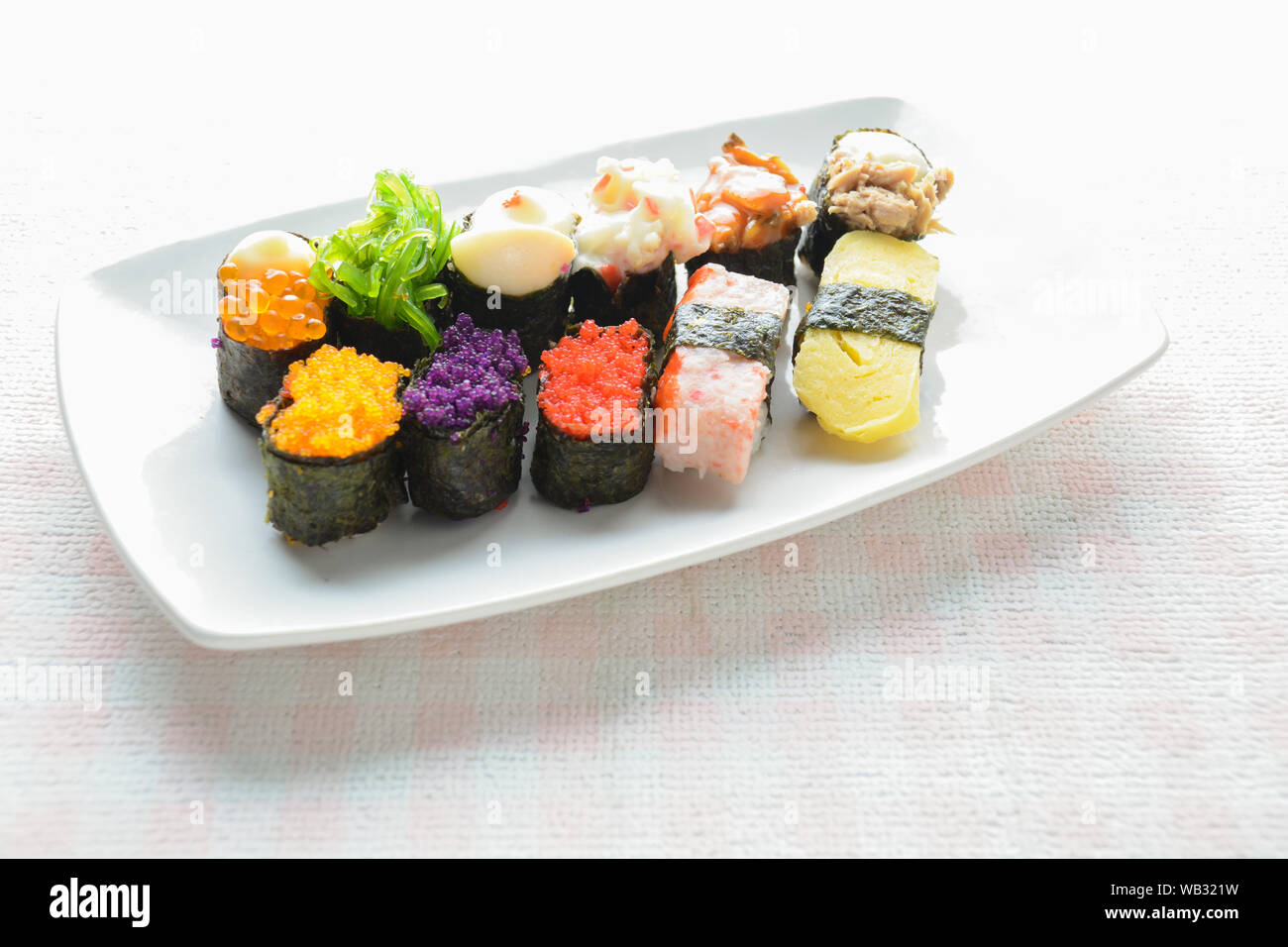 Sushi sur plaque blanche, thon, saumon, loup de mer, crevettes, oeufs sucrés sushi, cuisine japonaise Banque D'Images