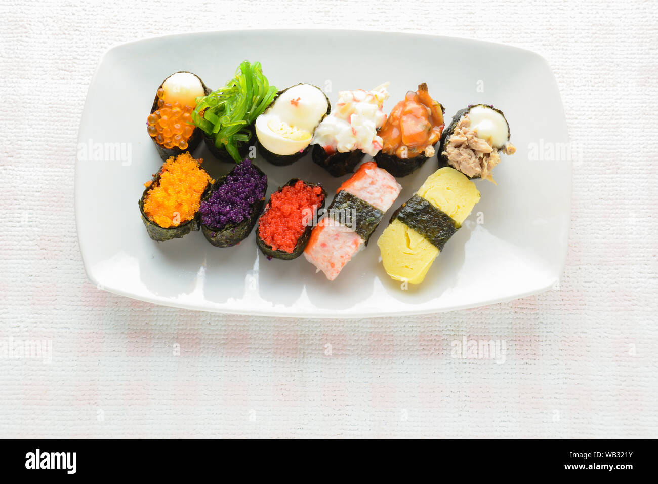 Sushi sur plaque blanche, thon, saumon, loup de mer, crevettes, oeufs sucrés sushi, cuisine japonaise Banque D'Images