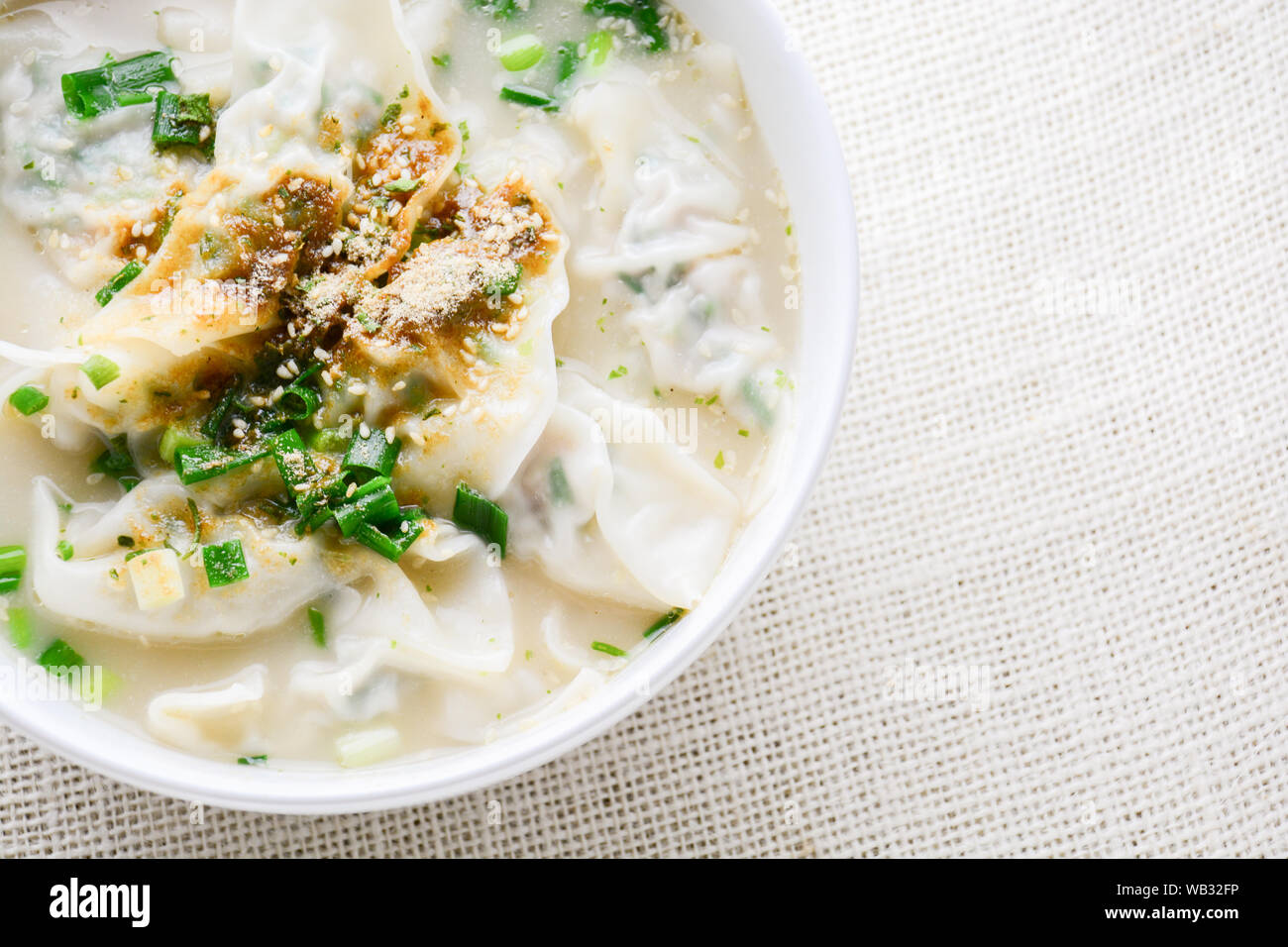 Wonton soup avec oignon de printemps servi dans un bol blanc, selective focus Banque D'Images