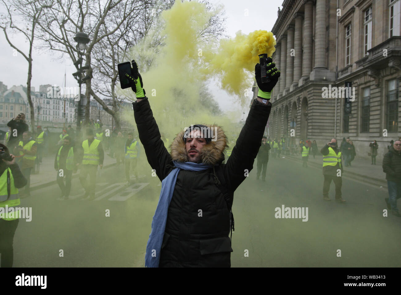 Gilet jaune portant des manifestants envoyer la fumée jaune dans l'air pendant une protestation mars en face de l'hôtel de ville à Paris le 5 janvier 2019 à Pari Banque D'Images
