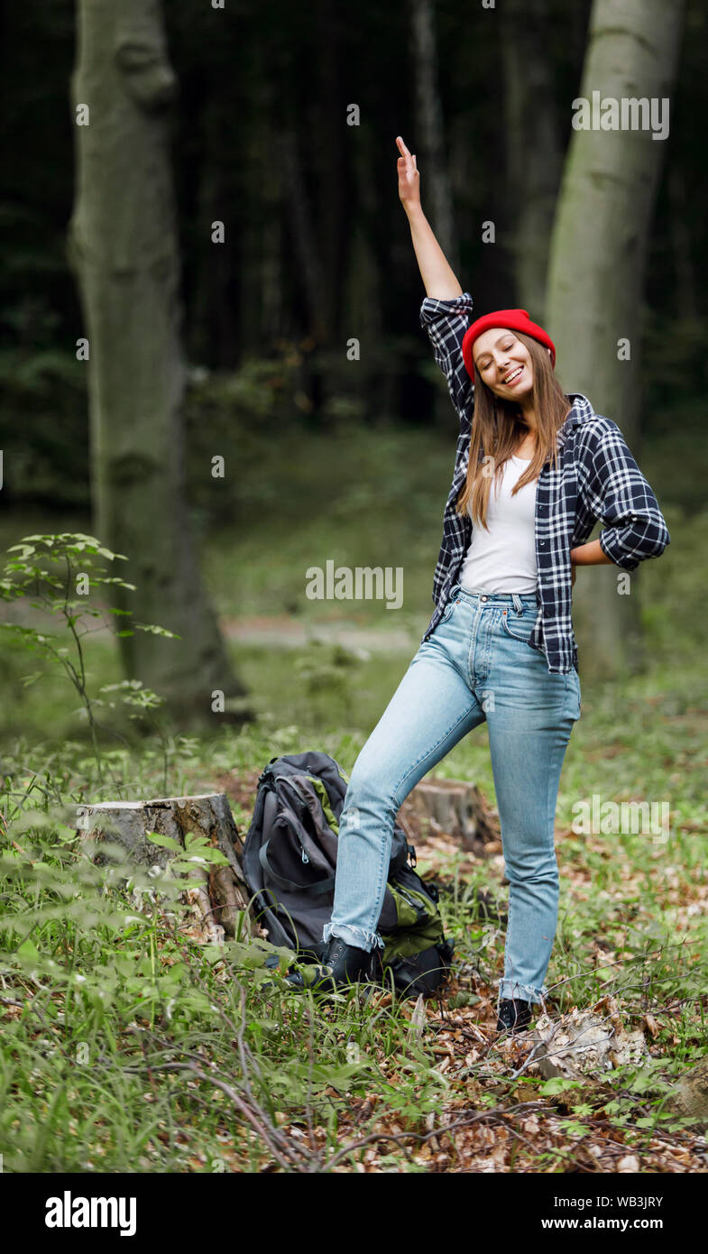 Young caucasian hiker brown haired woman backpacker autour et souriant pendant la randonnée dans la forêt de l'été Banque D'Images