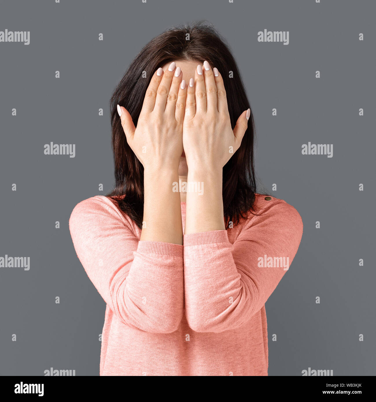 Young caucasian woman cachant son visage à partir de l'appareil photo Banque D'Images