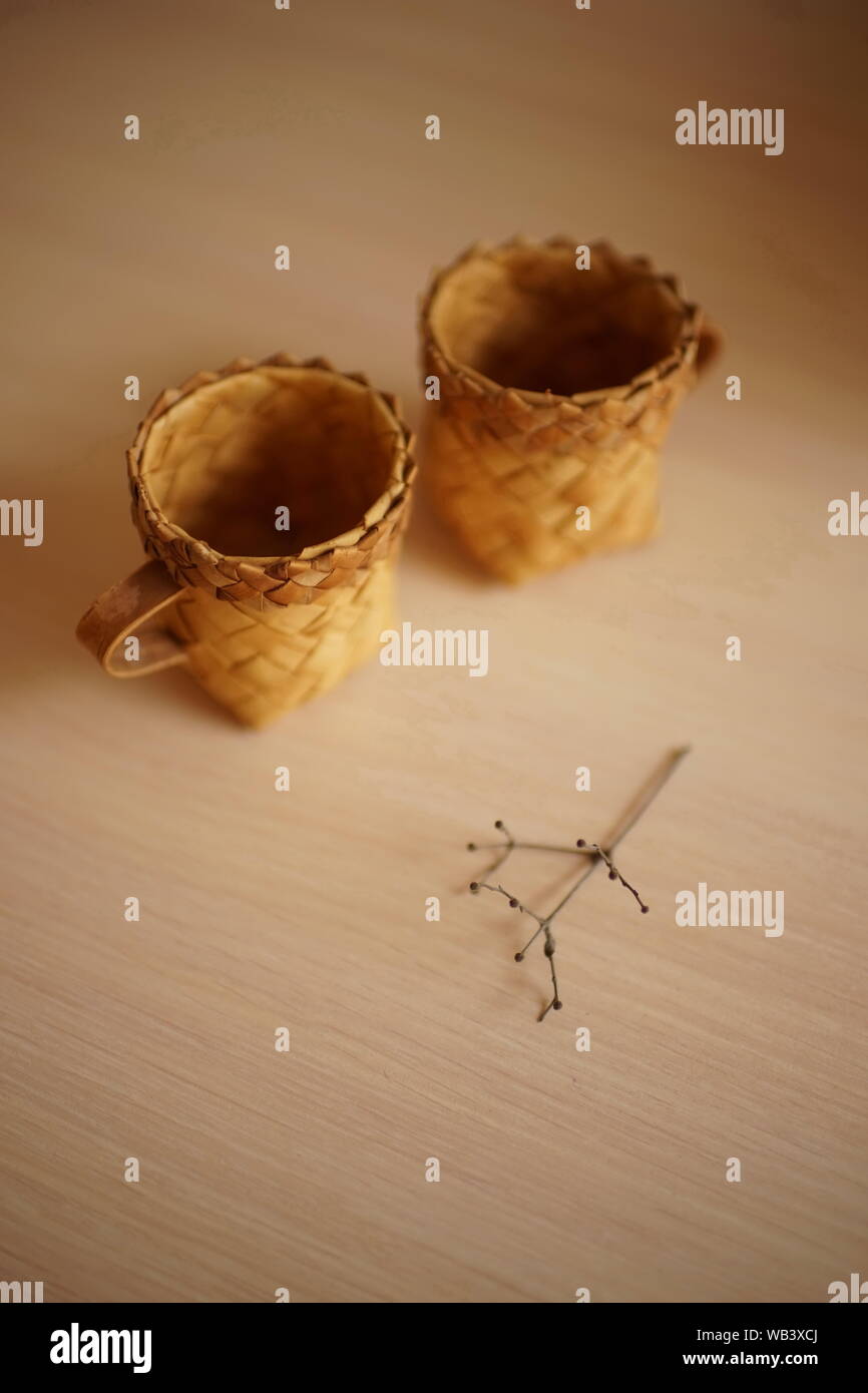 Deux tasses en osier et une fleur à sec sur la table Banque D'Images