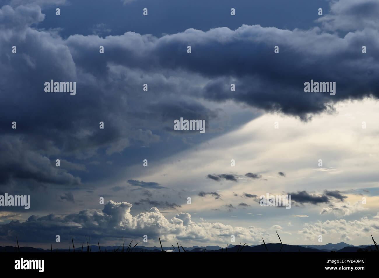 Nuage Gris hunk formations sur ciel tropical au-dessus de champ vert et de montagne , Nimbus en mouvement , Résumé fond de phénomène naturel , Thaïlande Banque D'Images