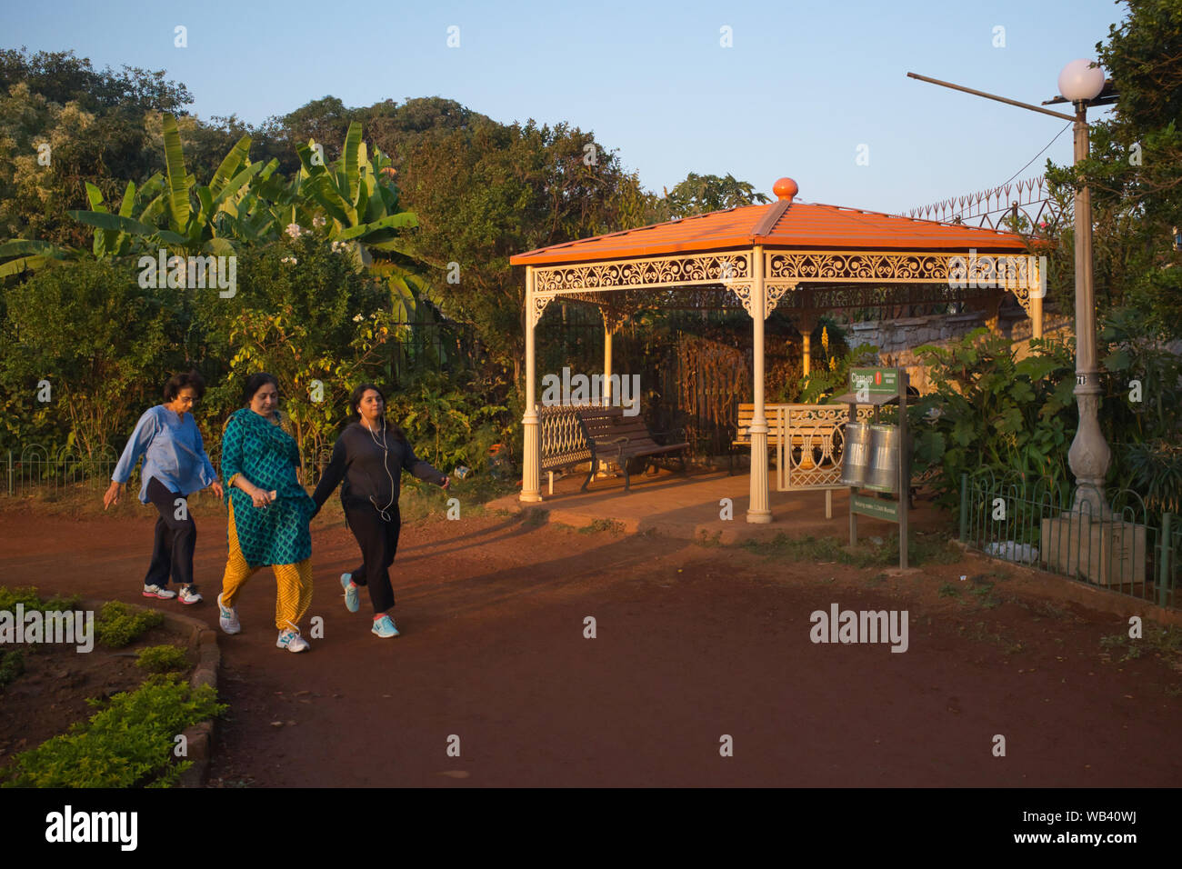 Sur une fin d'après-midi, trois femmes indiennes-pouvoir passer devant un ancien pavillon à jardins suspendus (Pherozeshah Mehta Gardens) à Mumbai, Inde Banque D'Images