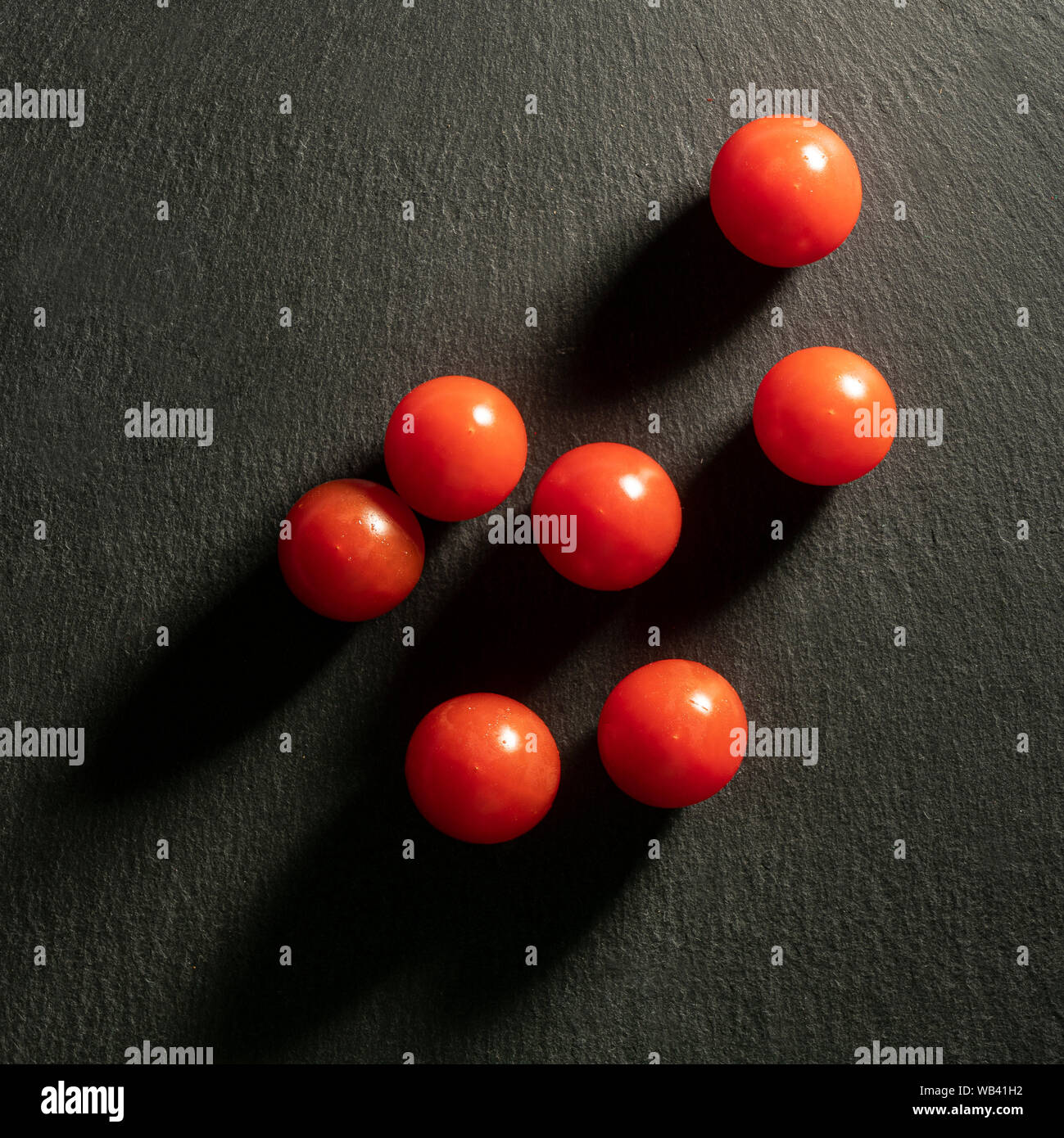 Quelques petites tomates sur une surface en pierre noire Banque D'Images