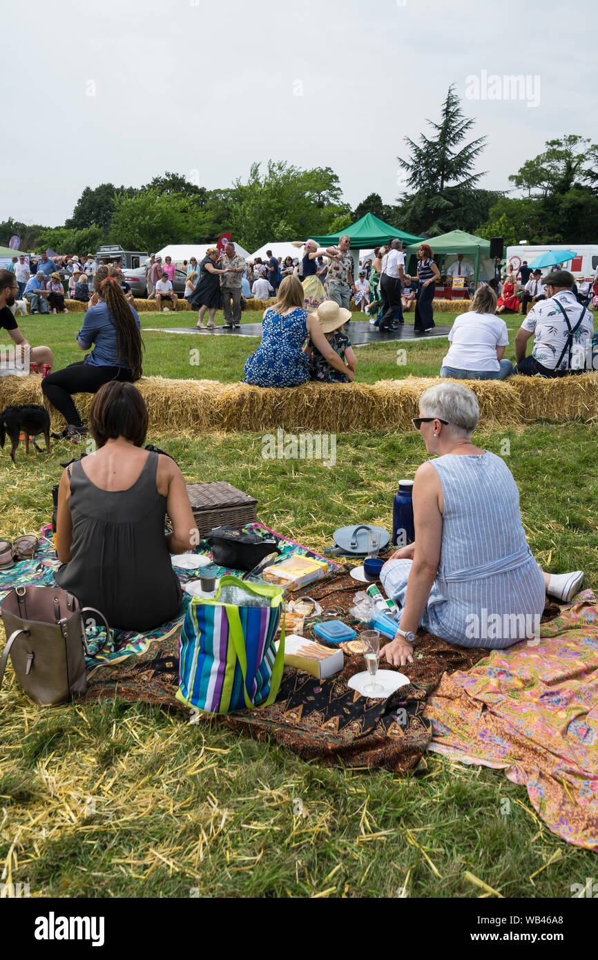 Spectateurs picnicing tout en regardant danser à l'ancien temps Helmingham Festival of Classic & Sports Cars 2019 Banque D'Images
