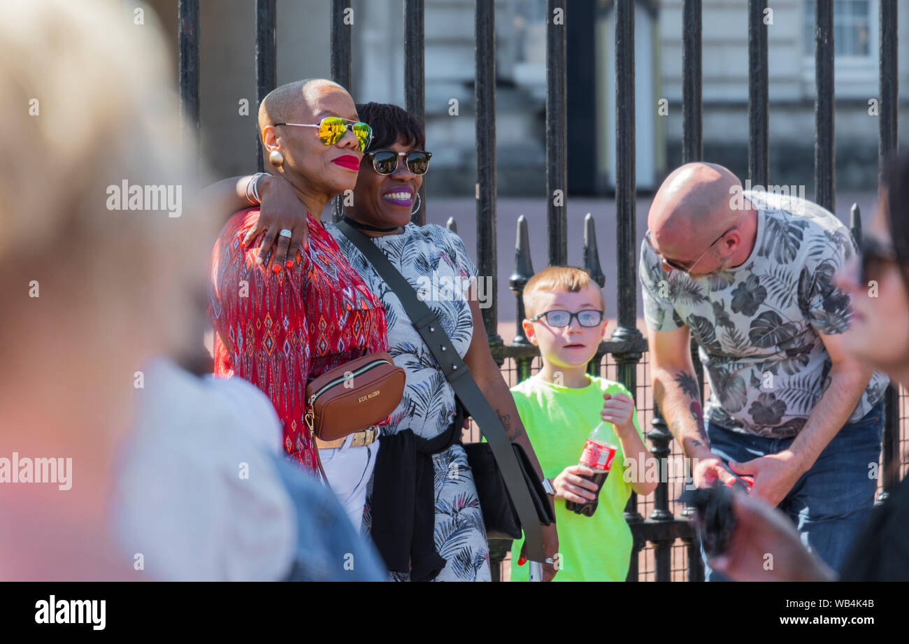 Une paire de femmes noires touristes posant pour une photo à l'extérieur de Buckingham Palace, Westminster, Londres, Angleterre, Royaume-Uni. Banque D'Images