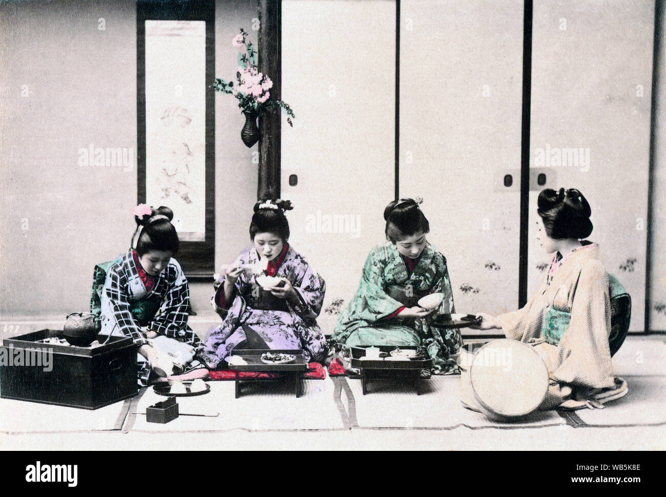 [ 1890 Japon - japonais Femmes ayant un repas ] - Avoir un repas. Quatre jeunes femmes en kimono sont assis sur le sol. Une femme tient un bac pour le son femme un bol. Une autre est de manger avec des baguettes, tandis que celui de gauche est de verser le thé. Albumen photographie sourcé par Kozaburo Tamamura (1856-1923 ?), années 1890, pour "Le Japon, décrit et illustré par les Japonais", selon l'édition de Shogun par le capitaine F Brinkley. Publié en 1897 par J B Millet Company, Boston, Massachusetts, USA. 19e siècle vintage albumen photo. Banque D'Images